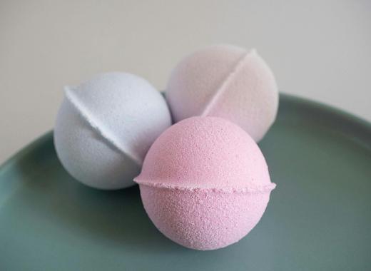 Three different colored (pink, blue, and beige) bath bombs sit resting on a plate.
